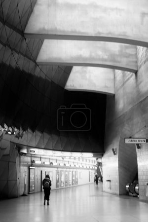Photo for A lonely young woman is walking at the tube station in London. She is surrounded by impressive architecture. - Royalty Free Image