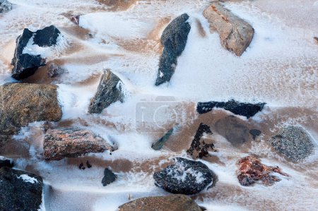 Photo for The sea wind has blown snow over the sand and rocks on a beach in the rural Finland. - Royalty Free Image