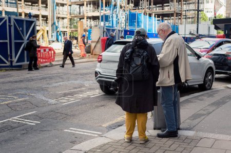 Photo for An elderly couple is looking at the map on the street corner. There is a construction site on the other side of the street. - Royalty Free Image