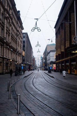 Photo for A man is standing in the middle of a street decorated with Christmas lights. He seems to be photographing the approaching tram. - Royalty Free Image