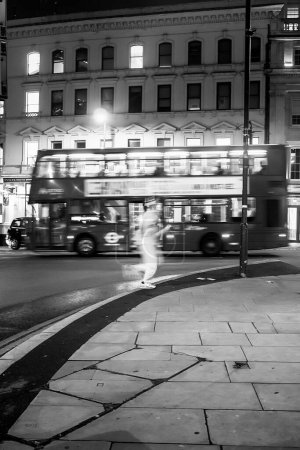 Photo for A person in white sporting clothes is running at a crossing in London. There's a double decker bus goiing by behind the runner. - Royalty Free Image