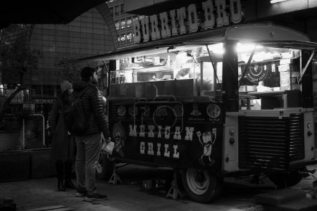 Photo for A couple is ordering burritos by a street food vendor in London, England. - Royalty Free Image