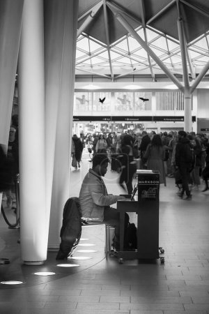 Photo for There are several pianos at the King's Cross Station in London and people are playing them while waiting for the train. - Royalty Free Image