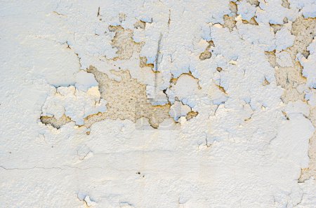 Gros plan de peinture à peler blanche sur un mur extérieur en stuc d'un bâtiment vintage.