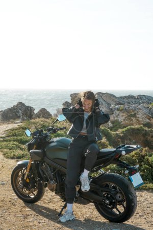 Hermosa chica ciclista y motocicleta Honda fresco en acantilados cerca del océano, Portugal, Peniche Travel, vacaciones en Europa, manera de motociclista.