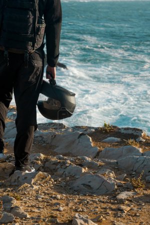 hommes motard tient un casque de moto dans ses mains sur les falaises près de l'océan, Portugal, Peniche Voyage, vacances en Europe, chemin de moto.