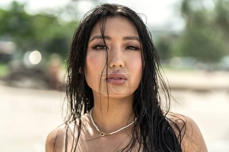 Photo for Beauty portrait of natural, attractive, young asian woman with wet hair and delicate makeup. Girl looking at the camera. Skin care. Tan. Beach sunny day on the island. - Royalty Free Image
