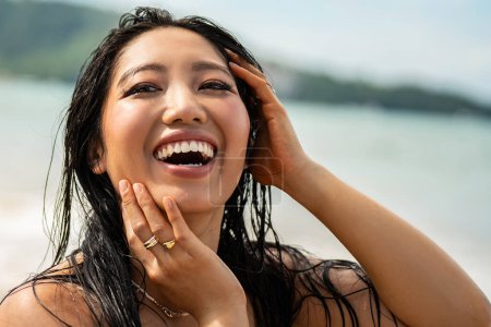 Photo for Photo of happy young asian woman with beautiful, big toothy smile. Girl with wet hair enjoying sunny day on the beach. Happy holiday lifestyle concept. Real people emotions. Traveler - Royalty Free Image