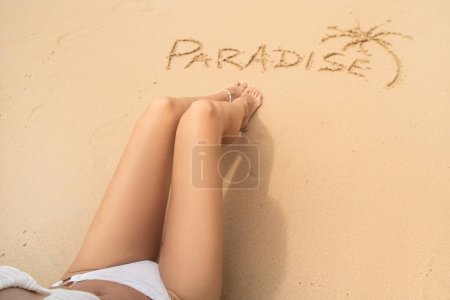 Photo for Word paradise and one palm on the sandy beach near the women's legs. Summer vacation concept. Realax. Travel. - Royalty Free Image