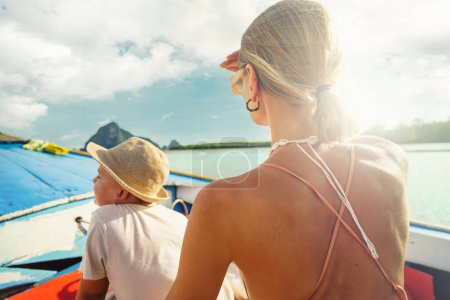 Téléchargez les photos : Maman et son fils voyageant en bateau à longue queue en Thaïlande. Concept vacances d'été. Voyages avec enfants. Aventure. - en image libre de droit