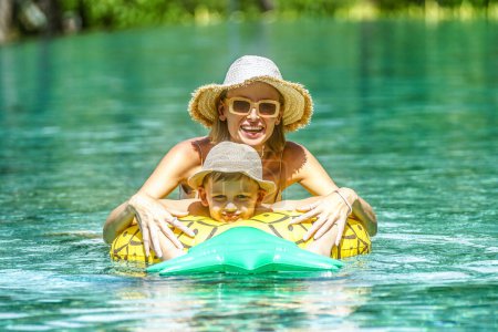 Téléchargez les photos : Bonne maman s'amuser à nager avec un petit enfant à la piscine extérieure de luxe. Vacances d'été. Style de vie familial. thaïlande - en image libre de droit