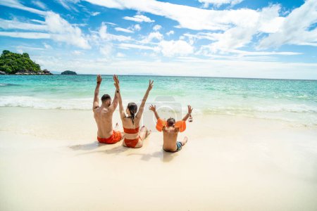 Photo for Photo of a happy family on tropical vacation, having fun on the tropical beach, playing with sea water. Little boy with parents. Tourist. - Royalty Free Image