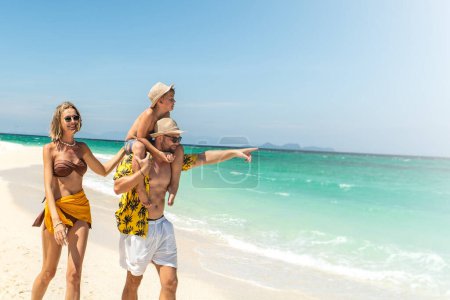 Photo for Joyful father, mother and son walking on the sandy tropical beach. Happy family holidays.  Active parents with children. Summer vibes. Copy space - Royalty Free Image