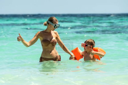 Foto de Photo of happy mother and her little son snorkeling on tropical beach, having fun together. Hobby. Water sports concept. Summer. Tourism - Imagen libre de derechos