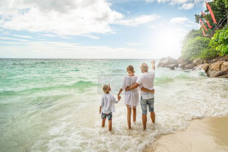 Foto de Happy family on the beach having fun on summer vacation. Father mother and one child enjoying sun. Holiday travel concept. Tourism - Imagen libre de derechos
