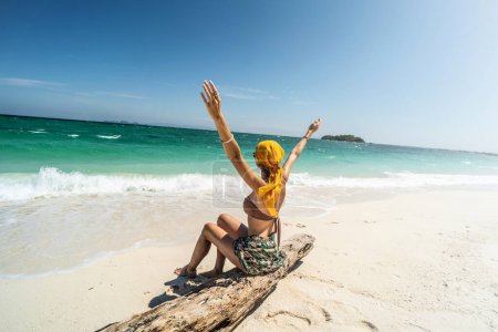 Photo for Beautiful happy woman having fun on a tropical beach, enjoying summer holidays, raising her hands up. Tourism, travel concept. - Royalty Free Image