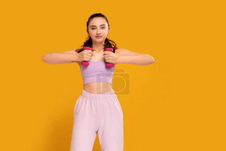 Foto de Young fitness woman in fashionable sporty clothes posing on the yellow studio background. A lo of copy space. Healthy lifestyle concept. Beautiful active student girl. - Imagen libre de derechos