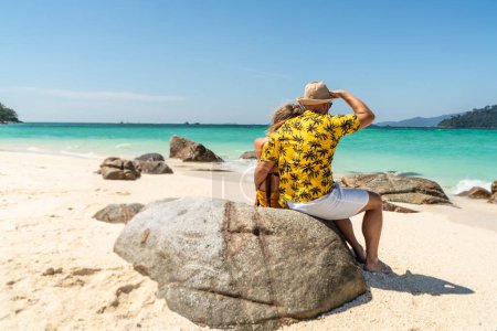 Photo for Romantic Couple Enjoying Beautiful seascape, sitting on the rock, on the tropical beach. Travel Vacation, real people Lifestyle Concept. Back view - Royalty Free Image