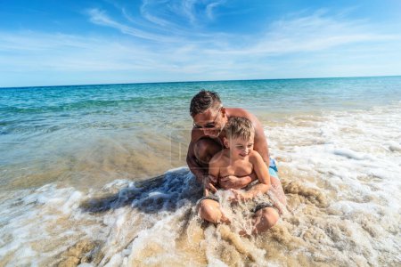 Foto de Sonriente chico y yo divirtiéndonos juntos en el océano. Papá con su hijo jugando en la playa. Actividades de verano. Estilo de vida real. Turismo. - Imagen libre de derechos