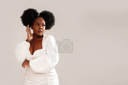 Foto de Retrato de belleza de mujer atractiva con peinado afro y maquillaje delicado mirando hacia otro lado, posando sobre fondo de estudio. Chica con pestañas largas .Copiar el espacio - Imagen libre de derechos
