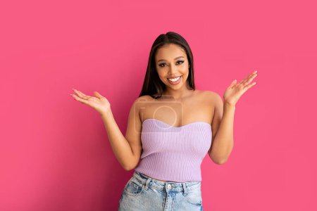 Photo for Joyful woman laughing, looking at the camera, posing on a pastel pink Studio Background. Real people emotions, toothy smile. Fashionable young girl in violet top and jeans.. A lot of copy space. - Royalty Free Image
