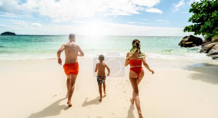 Tropical summer vacations. Happy family having fun together on the beach. Father, mother, son running. Thailand, Koh Lipe.