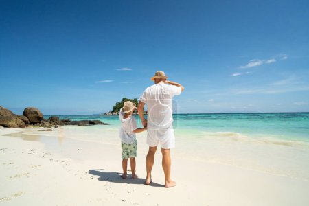 Photo for Father and son holding hands, having fun together, walking on the tropical beach. Fathers day. Summer vacation. Copy space - Royalty Free Image