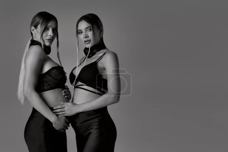 Photo for Photo of elegant pregnant young women, twins sisters. Studio shot of a ladies who are expecting babies. Free space for text. - Royalty Free Image