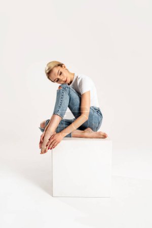 Photo for Blonde caucasian woman posing in studio, wearing casual clothes, jeans and white tshirt. Full length photo. Studio shot. Copy space. - Royalty Free Image