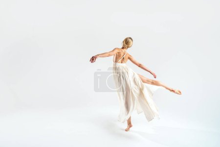Foto de Bailarina de ballet bailando sobre fondo de estudio en maxi vestido. Vista trasera. Copiar espacio. Longitud completa. - Imagen libre de derechos