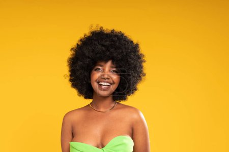 Photo for Beauty Girl with delicate natural Makeup smiling to the camera. Glamour young woman with afro hairstyle. Yellow studio background. Copy space. Real people emotions. - Royalty Free Image