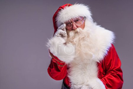 Téléchargez les photos : Le vrai vieux Père Noël regardant la caméra, posant sur un fond de studio. Joyeux Noël et bonne année ! Espace de copie. Vente de Noël, concept de réduction. - en image libre de droit