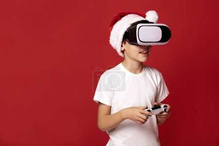 Photo for Fascinated little boy in santa claus red hat using VR virtual reality goggles. Christmas time, xmas gifts. - Royalty Free Image