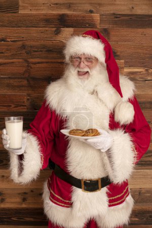 Photo for Funny real Santa Claus with glass of milk and delicious cookies. - Royalty Free Image
