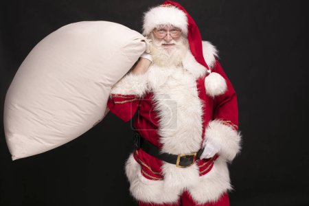 Photo for Real Santa Claus carrying big sack with christmas gifts. - Royalty Free Image