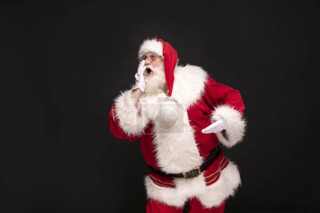 Téléchargez les photos : Le vrai Père Noël crie sur fond de studio noir. Noël arrive! - en image libre de droit