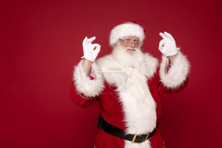 Photo for Happy real Santa Claus is smiling, posing on red studio background. - Royalty Free Image