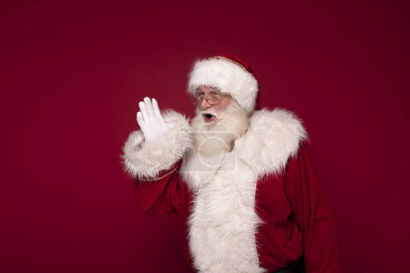 Téléchargez les photos : Le vrai Père Noël crie sur fond de studio rouge. Noël arrive! - en image libre de droit