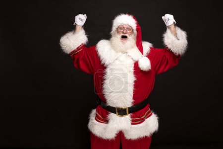 Téléchargez les photos : Le vrai Père Noël crie sur fond de studio rouge. Noël arrive! - en image libre de droit