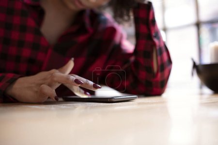 Foto de Primer plano de la mano de la mujer que utiliza el teléfono inteligente en la mesa de madera, la búsqueda de información en línea en la pantalla táctil. - Imagen libre de derechos