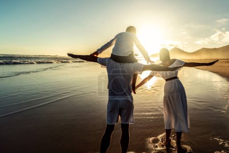 Photo for Happy young family of three spending free time outdoors, walking and having fun on seaside. Back view. Copy space. Island vibes. Sunset light. Vacation - Royalty Free Image