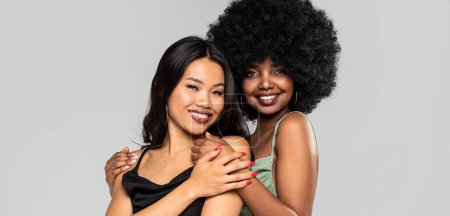 Téléchargez les photos : Beauté asiatique femme posant avec son ami avec afro coiffure. Filles gaies et élégantes debout ensemble, regardant la caméra et souriant joyeusement. Espace de copie. De vraies personnes. - en image libre de droit
