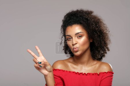 Photo for Playful positive curly haired woman send a kiss, shows a happy peace gesture. Real people emotions concept. Studio shot. Beauty portrait. - Royalty Free Image