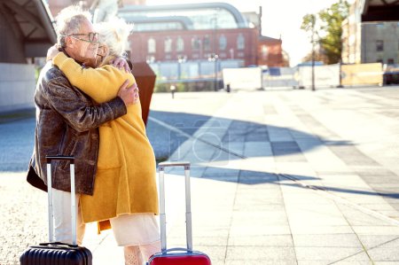 Photo for Seniors couple saying goodbye or hello to each other on the train station. Two mature people wearing protective mask, hugging. Travel and relationship concept during a pandemic. Outdoor photo. - Royalty Free Image