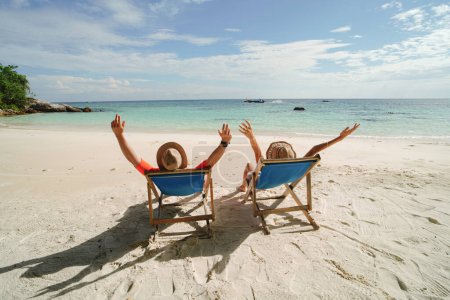 Téléchargez les photos : Vacances d'été tropicales. Couple relaxant sur la plage, regardant la mer, assis sur les chaises longues de la plage. Thaïlande, Asie. Concept de voyage. Destination de rêve. - en image libre de droit