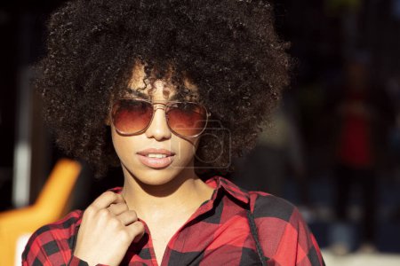 Photo for Portrait of smiling, fashionable African American young woman with afro hair wearing stylish sunglasses. - Royalty Free Image