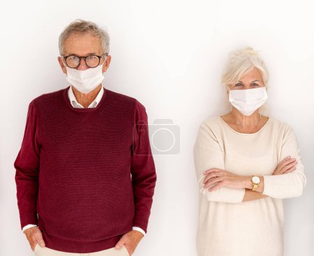 Téléchargez les photos : Deux personnes âgées posant avec un masque recouvert sur le fond blanc du studio. - en image libre de droit