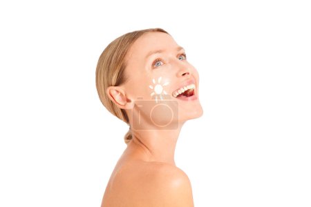 Foto de Mujer caucásica con sol blanco en la cara sonriente, protección solar. Mujer rubia mirando hacia otro lado. Cuidado del cuerpo y la piel. Estudio shoo - Imagen libre de derechos