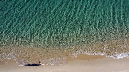 Téléchargez les photos : Vue aérienne de la femme marchant sur la plage de sable avec des vagues océaniques freinant sur la côte. Des vibrations estivales. Sardaigne. Concept de voyage - en image libre de droit