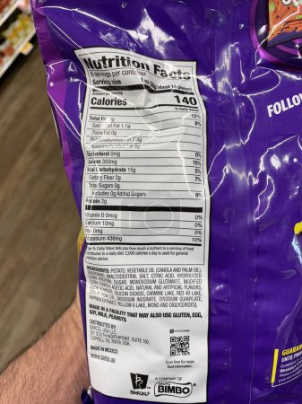 Photo for Grovetown, Ga USA - 01 13 23: Grocery store Hand holding Taki chips fuego ingredients label - Royalty Free Image